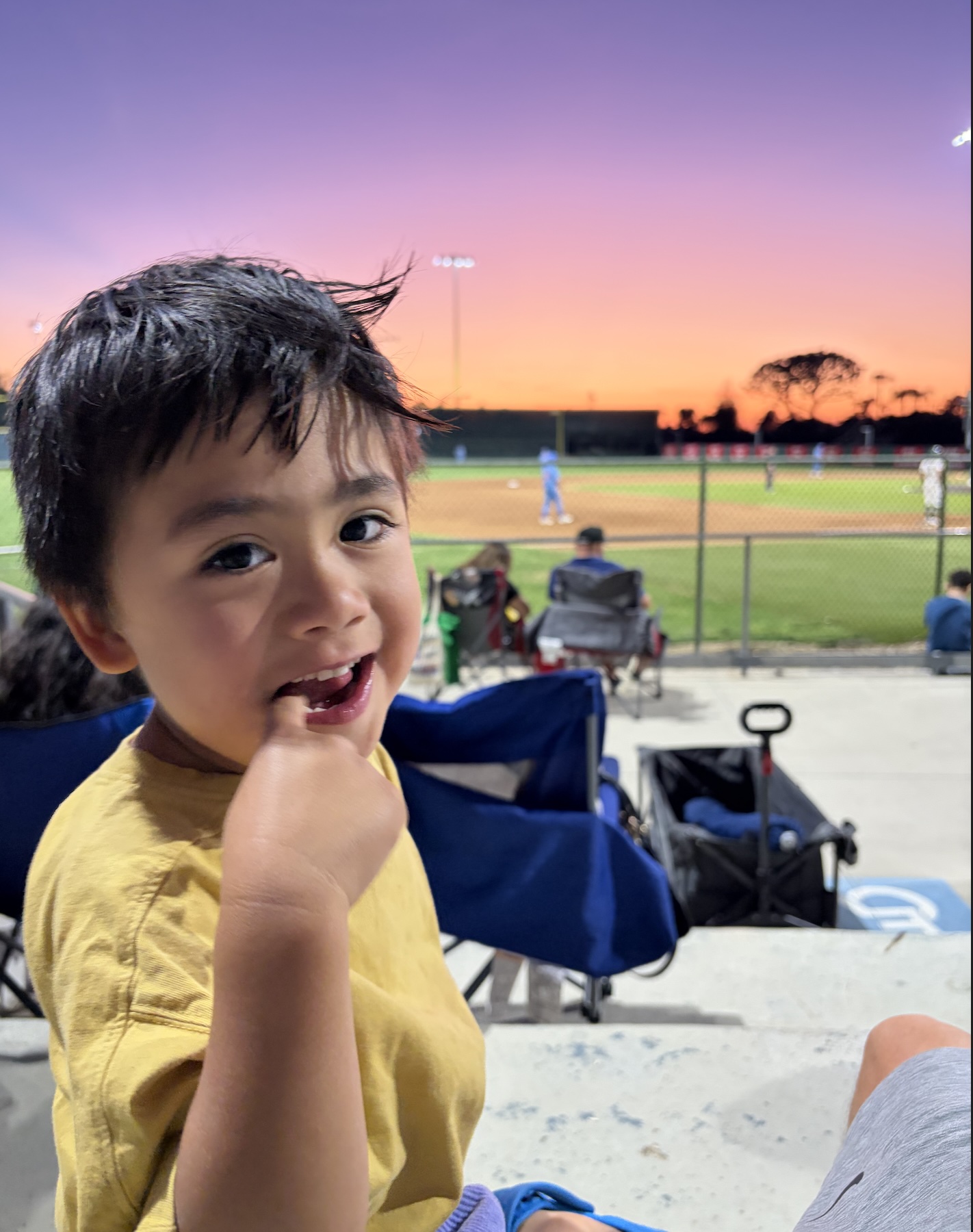 Augie smiling at a baseball field at sunset